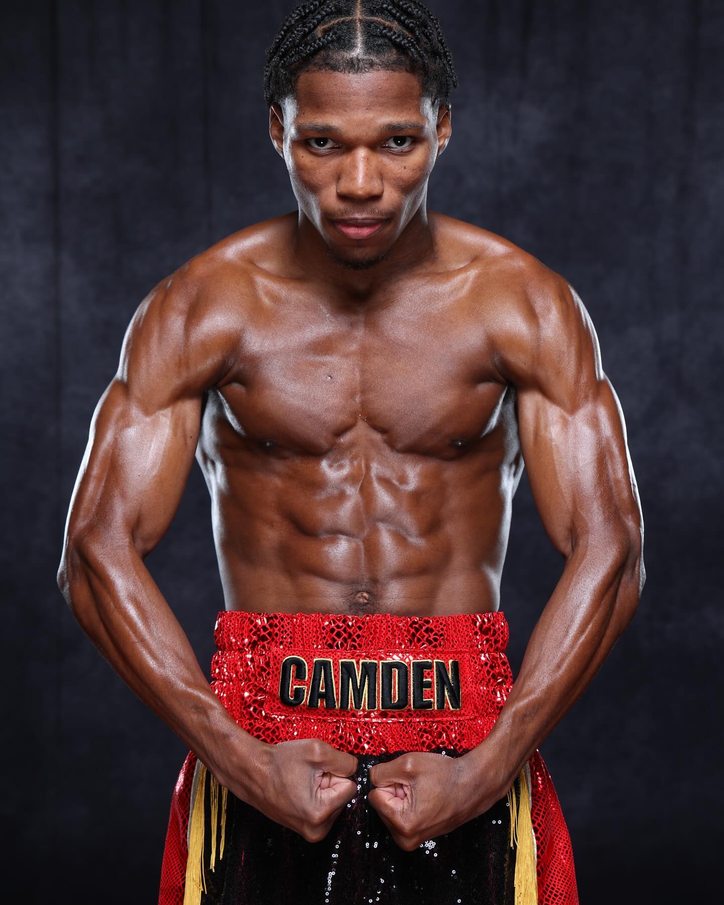 Raymond Ford poses in red boxing trunks against a dark backdrop